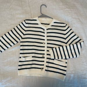 Knitted sweater cardigan with gold button closures.